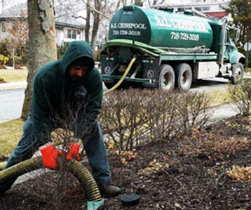 Worker Handling A Hose For A Septic Service With An A&L Cesspool Truck In The Background.