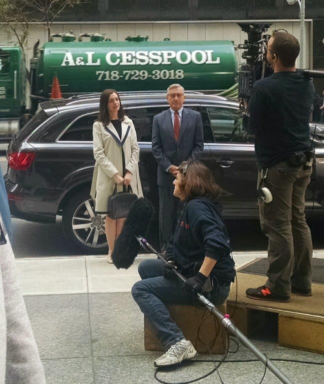 Film crew shooting a scene outdoors with two actors in front of an A&L Cesspool truck