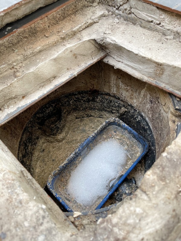 Grease Trap Filled With Residue And Foam In A Concrete Enclosure